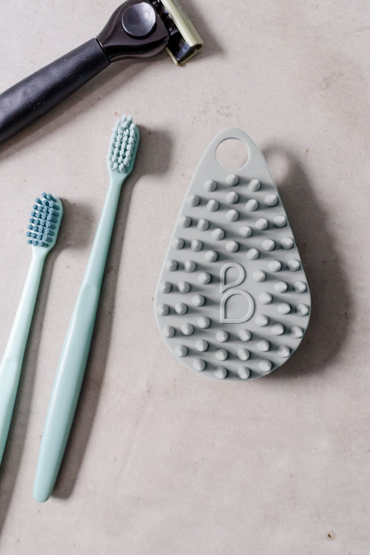 Scrub-dub body scrubber in light gray with tooth brush and razor.