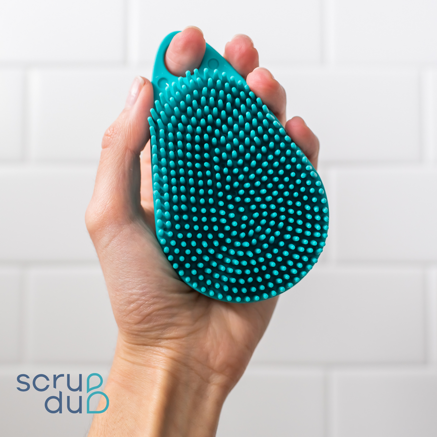 A person holding a Scalp and Body Scrubber - Tahiti Teal in their hand while scrub-dubbing.