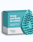 A teal scalp and body scrubber with soft bristles is displayed next to its box packaging, labeled "The scrub-dub® Scalp and Body Scrubber," featuring a quote: "You're breaking up with me?! - Your Loofah." The brand name reads "scrub-dub®." This exfoliating brush perfects your skincare routine.