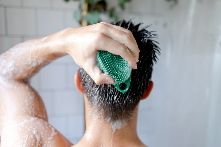 Man massages scalp with silicone body scrubber using shampoo spikes.