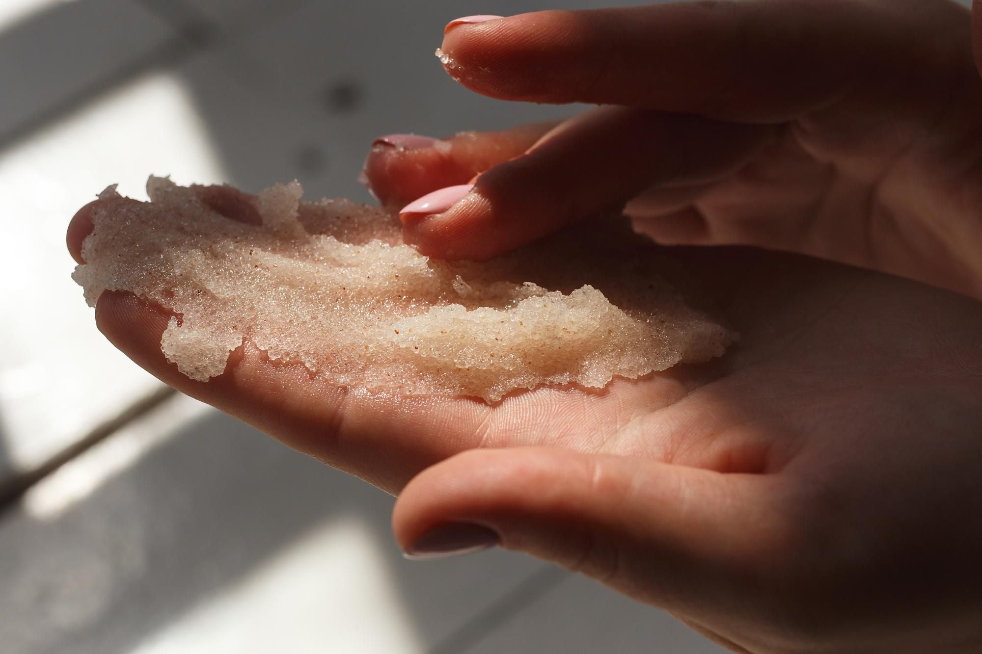 Hands moving sugar scrub into palm.