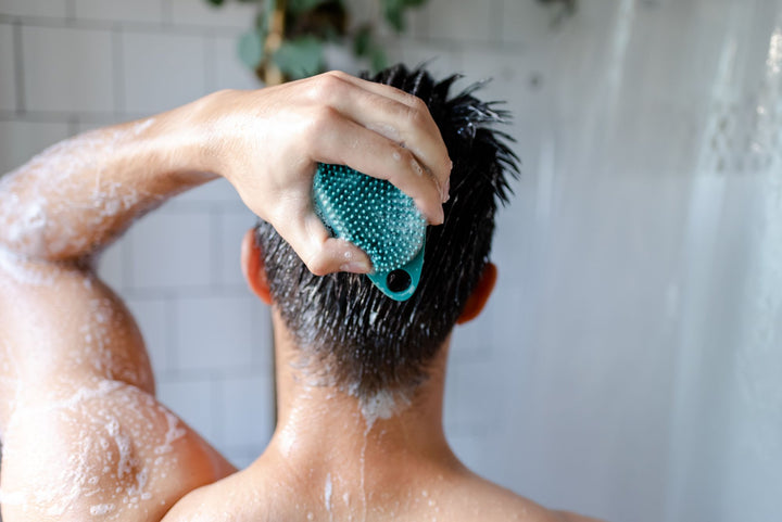 Man in shower scrubbing body with Scrub-dub teal body scrubber.