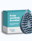 A blue "Scrub-dud™" scalp and body scrubber with gentle bristles, next to its packaging with the text "scalp and body scrubber - you're breaking up with me?!