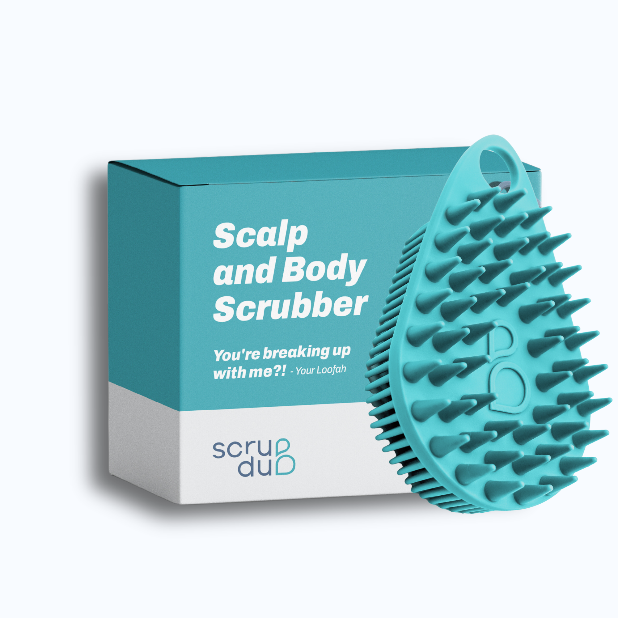 A teal scalp and body scrubber with soft bristles is displayed next to its box packaging, labeled &quot;The scrub-dub® Scalp and Body Scrubber,&quot; featuring a quote: &quot;You&#39;re breaking up with me?! - Your Loofah.&quot; The brand name reads &quot;scrub-dub®.&quot; This exfoliating brush perfects your skincare routine.