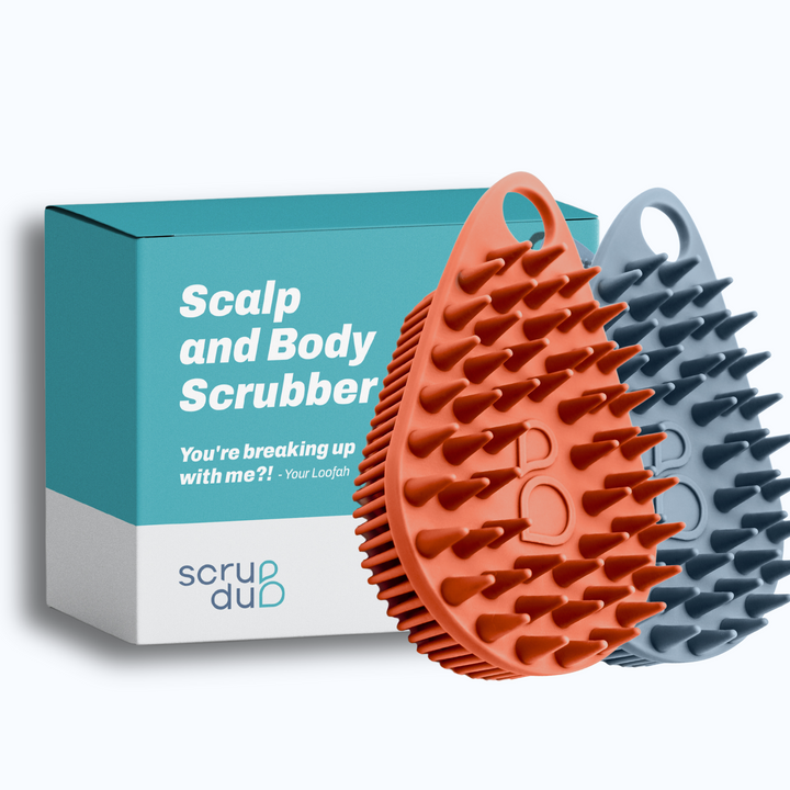 The scrub-dub® Scalp & Body Scrubber Duo Pack from Scrub-dub™ features two silicone scalp and body scrubbers in orange and gray, presented alongside a box labeled "Scalp and Body Scrubber." These antimicrobial scrubbers are perfect for maintaining hygiene while traveling, making them ideal travel-friendly companions.